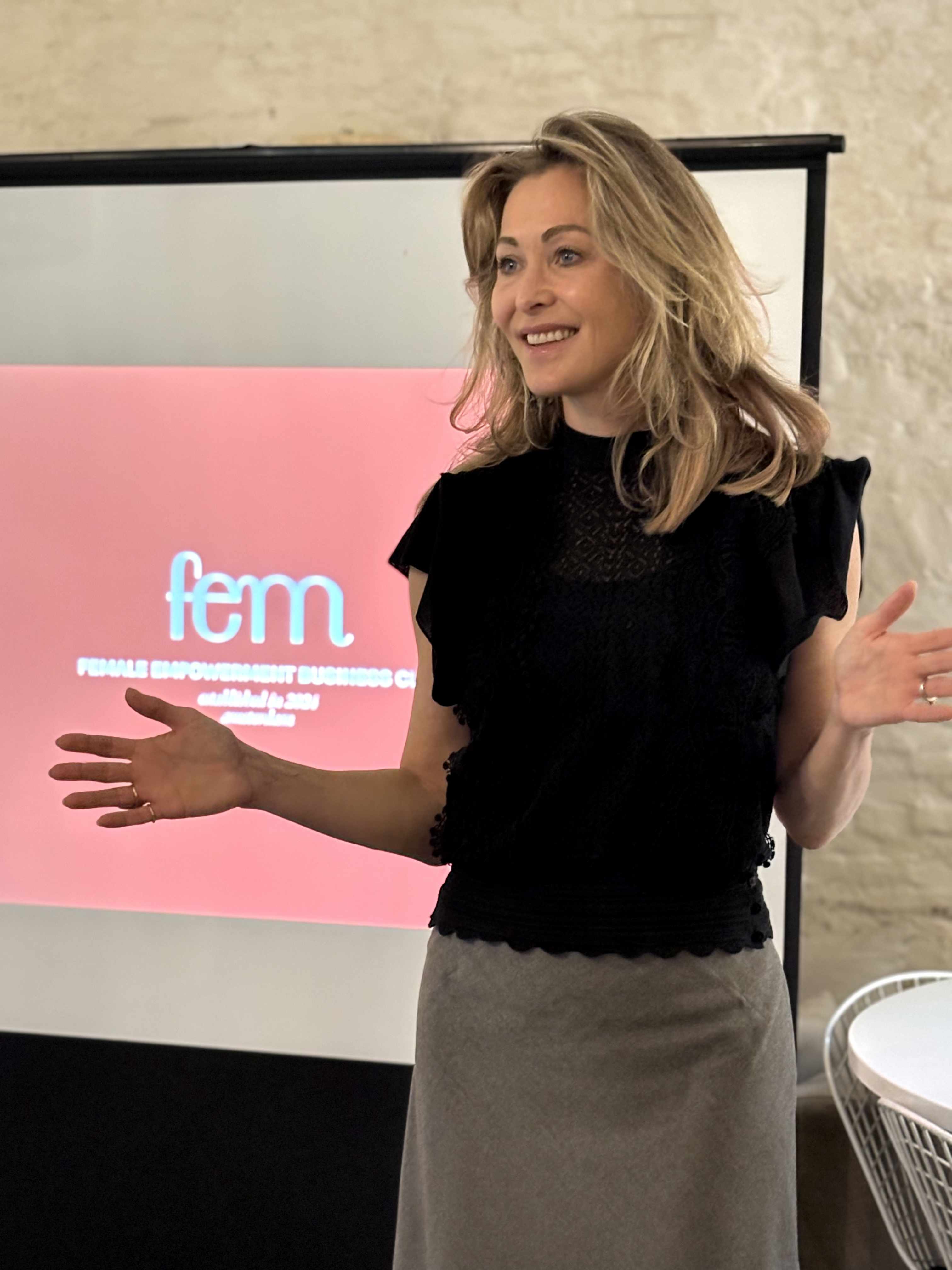 Sandra presenting at FEM Business Club with pink FEM banner